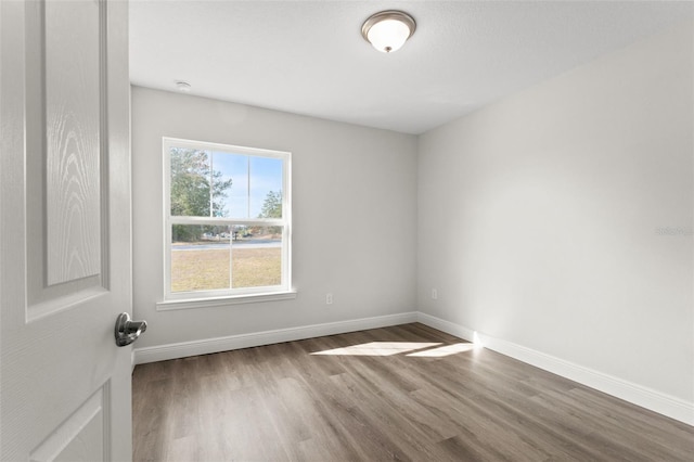 spare room with baseboards and wood finished floors