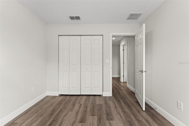 unfurnished bedroom with visible vents, baseboards, and wood finished floors