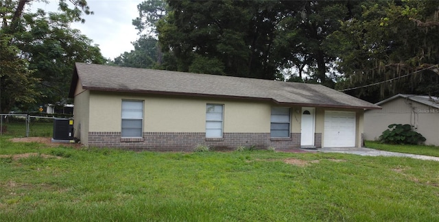 ranch-style house featuring a front lawn, central AC unit, and a garage