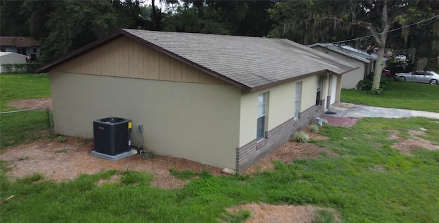 view of side of property featuring central air condition unit and a lawn