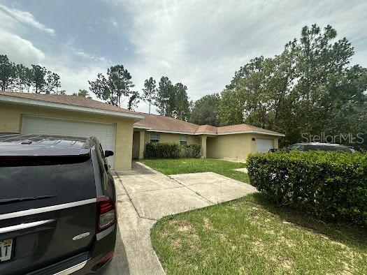 ranch-style home featuring a garage, driveway, and a front lawn