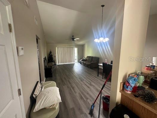 interior space with lofted ceiling, ceiling fan with notable chandelier, and wood finished floors