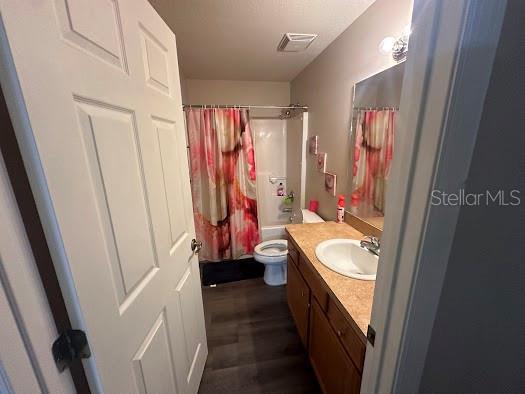 full bathroom with vanity, toilet, shower / tub combo with curtain, and hardwood / wood-style flooring