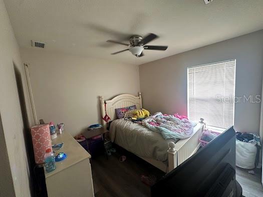 bedroom with ceiling fan, wood finished floors, and visible vents