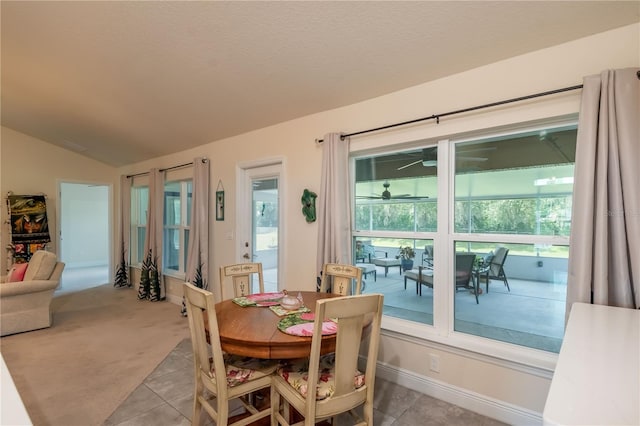 dining area featuring light colored carpet, vaulted ceiling, and plenty of natural light