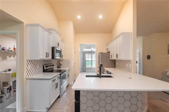 kitchen featuring light tile patterned flooring, kitchen peninsula, white cabinetry, and appliances with stainless steel finishes