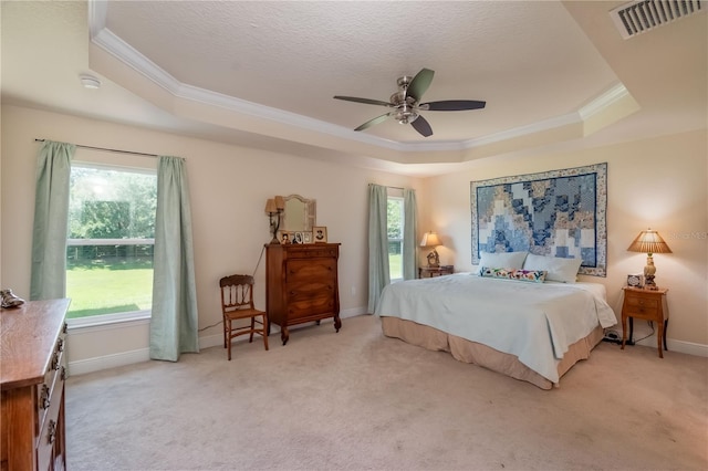 carpeted bedroom featuring a tray ceiling, ceiling fan, and ornamental molding