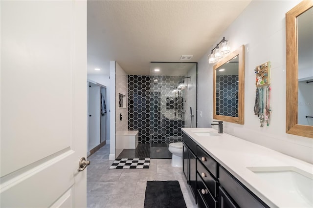 bathroom with tile patterned floors, vanity, toilet, and tiled shower