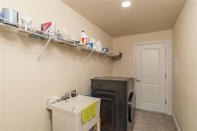 clothes washing area with separate washer and dryer, sink, light tile patterned flooring, and a textured ceiling