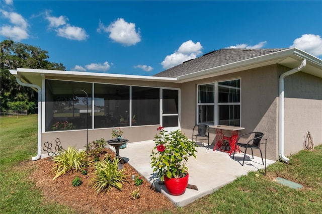 rear view of property with a sunroom, a yard, and a patio