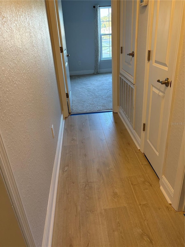 hallway with light hardwood / wood-style floors