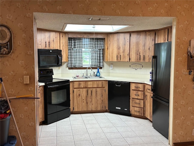 kitchen featuring a skylight, light tile patterned floors, sink, black appliances, and a textured ceiling