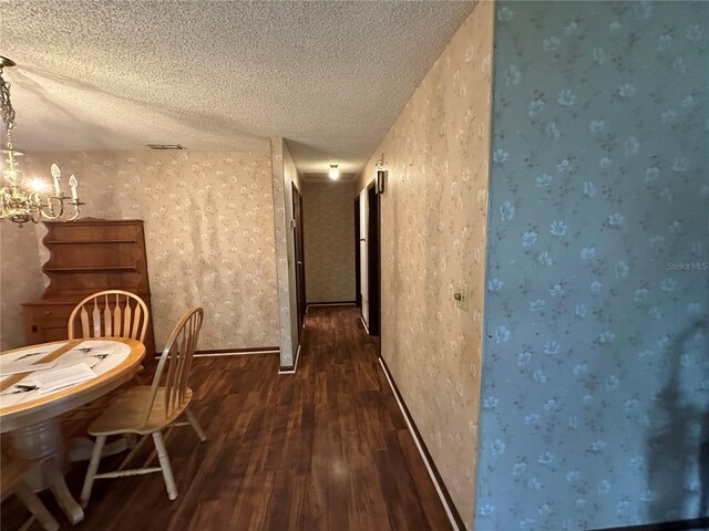 unfurnished dining area featuring a textured ceiling, an inviting chandelier, and dark hardwood / wood-style floors