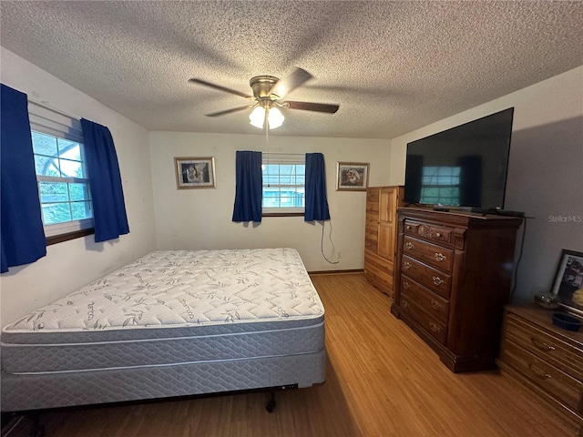 bedroom featuring a textured ceiling, wood-type flooring, and ceiling fan