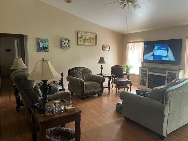 living room with hardwood / wood-style floors, lofted ceiling, ceiling fan, and a fireplace