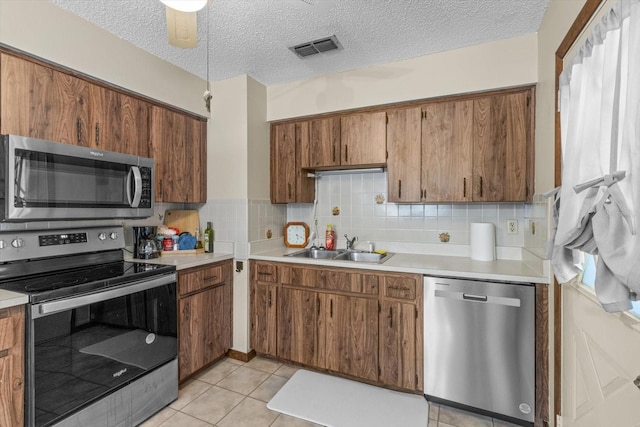 kitchen with ceiling fan, backsplash, light tile patterned floors, a textured ceiling, and stainless steel appliances