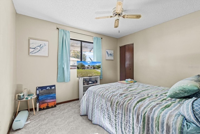 bedroom with ceiling fan, light carpet, a textured ceiling, and a closet