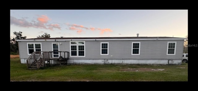 back of house at dusk with a lawn