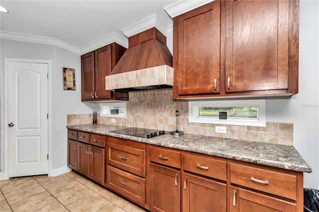 kitchen featuring black electric stovetop, backsplash, light stone counters, custom exhaust hood, and light tile patterned floors