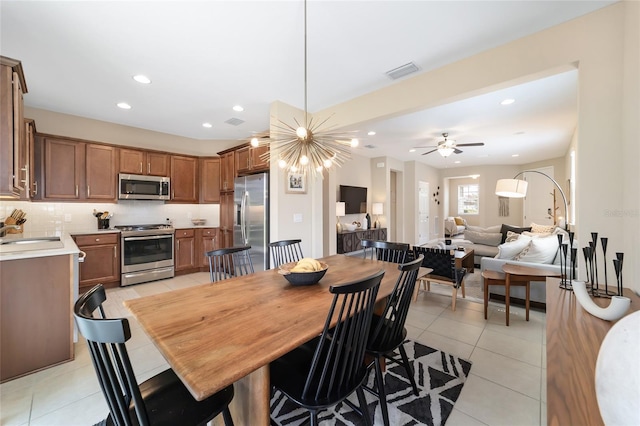 tiled dining space with sink and ceiling fan with notable chandelier