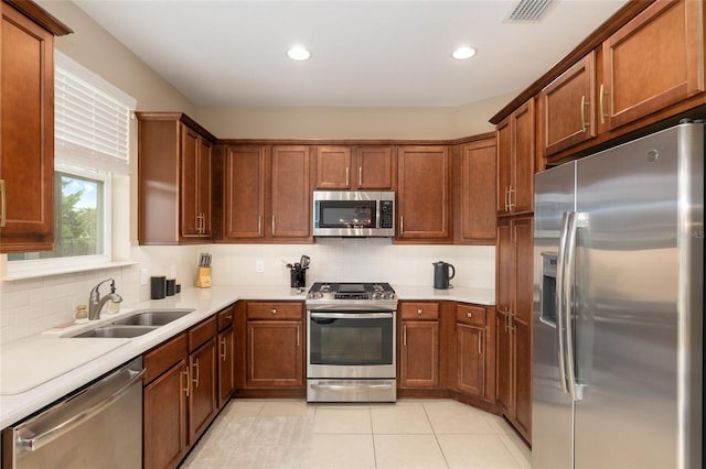 kitchen with backsplash, stainless steel appliances, light tile patterned flooring, and sink