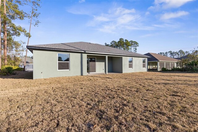 rear view of house featuring stucco siding