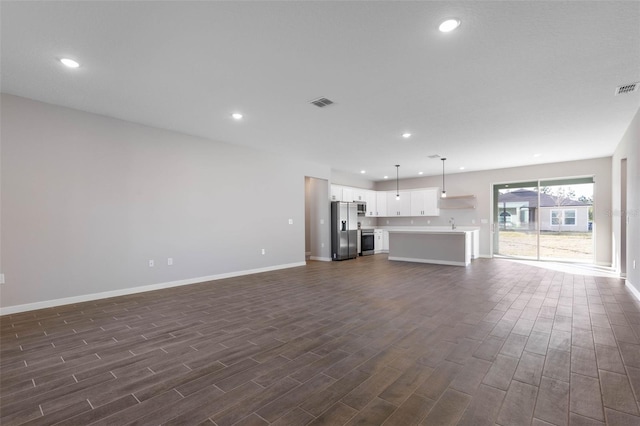 unfurnished living room with dark wood-style flooring, visible vents, and recessed lighting