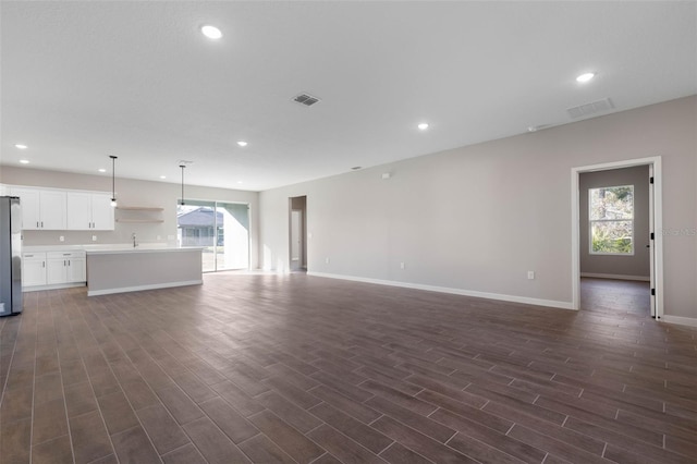 unfurnished living room featuring dark wood-style floors, visible vents, a wealth of natural light, and recessed lighting