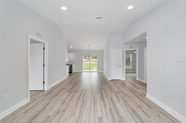 unfurnished living room featuring light hardwood / wood-style floors, an inviting chandelier, and lofted ceiling