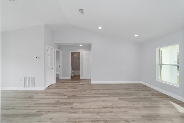 unfurnished room featuring visible vents, light wood-style flooring, baseboards, and lofted ceiling
