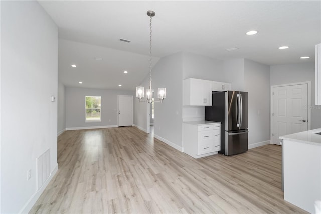 kitchen with lofted ceiling, white cabinets, light countertops, and freestanding refrigerator