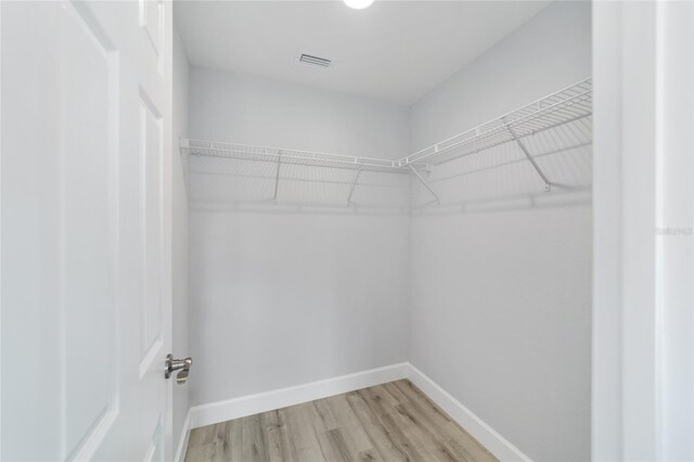 walk in closet with light wood finished floors and visible vents