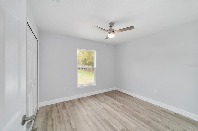 unfurnished bedroom featuring a ceiling fan, light wood-style flooring, baseboards, and a closet