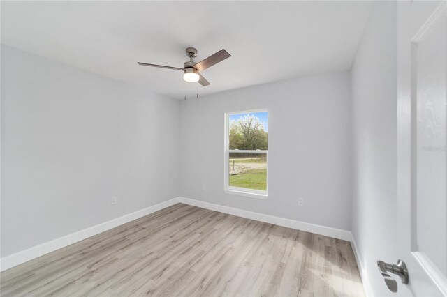 spare room featuring baseboards, light wood-style floors, and a ceiling fan