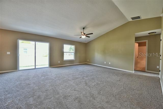 unfurnished room with baseboards, visible vents, carpet floors, lofted ceiling, and ceiling fan