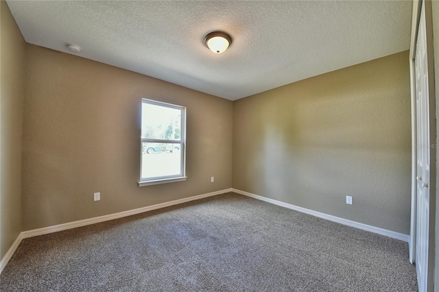 empty room with carpet and a textured ceiling