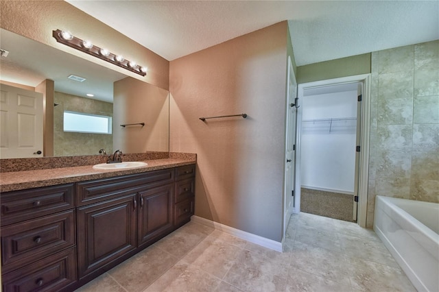 bathroom with a textured ceiling, vanity, and tile patterned floors