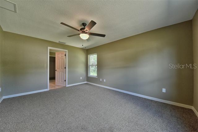 carpeted spare room featuring visible vents, baseboards, a textured ceiling, and ceiling fan