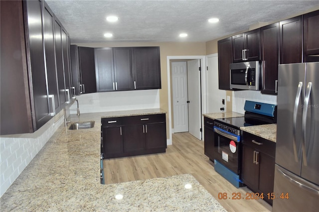 kitchen with sink, decorative backsplash, light hardwood / wood-style flooring, and appliances with stainless steel finishes