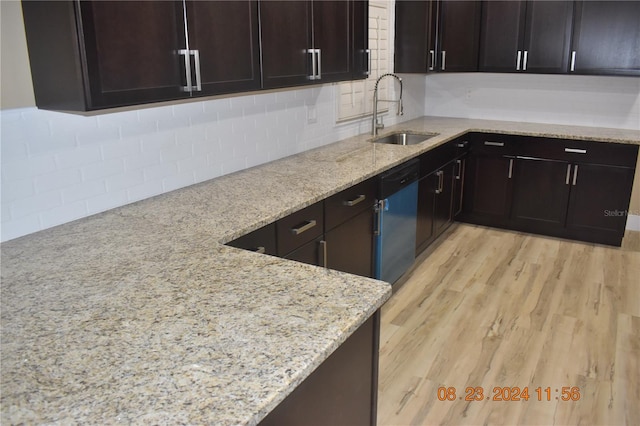 kitchen with sink, light stone counters, decorative backsplash, and light wood-type flooring