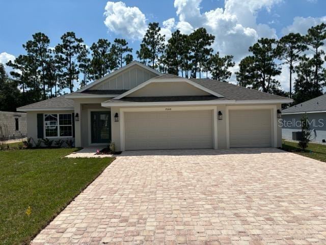 view of front of house featuring decorative driveway, stucco siding, board and batten siding, a garage, and a front lawn