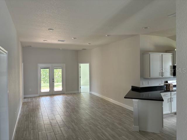 unfurnished living room featuring hardwood / wood-style flooring, french doors, and a textured ceiling