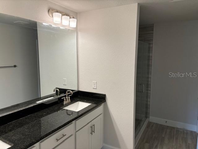 bathroom with hardwood / wood-style flooring, an enclosed shower, and vanity