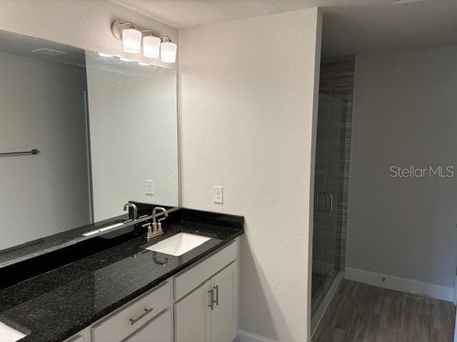 full bath with wood finished floors, a shower stall, vanity, and baseboards