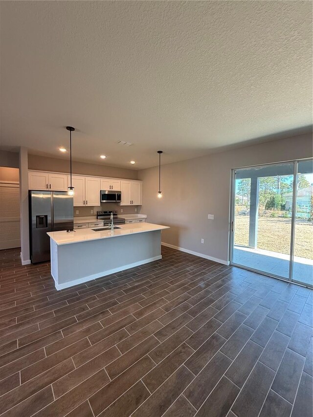 kitchen with sink, white cabinetry, decorative light fixtures, a center island with sink, and appliances with stainless steel finishes