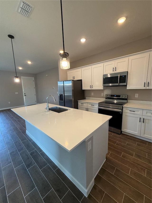 kitchen featuring white cabinetry, sink, decorative light fixtures, and appliances with stainless steel finishes