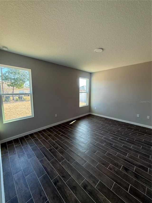 spare room featuring a textured ceiling and dark hardwood / wood-style flooring