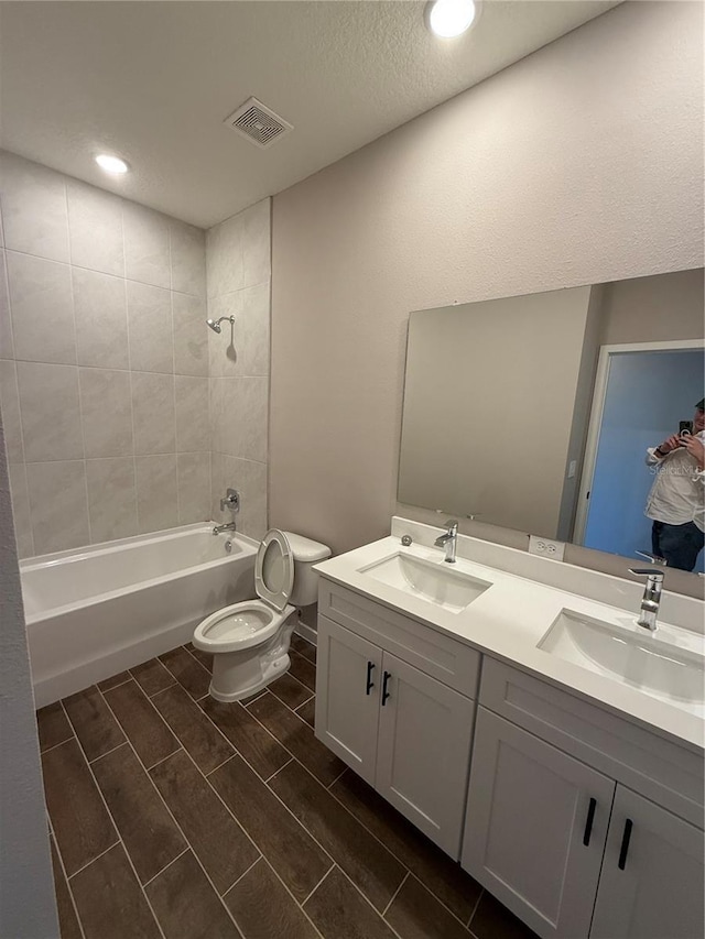 full bathroom featuring tiled shower / bath combo, vanity, and toilet