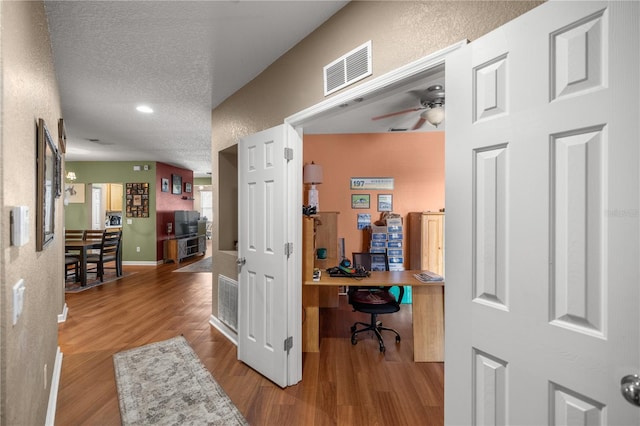 interior space featuring a textured ceiling, light hardwood / wood-style flooring, and ceiling fan