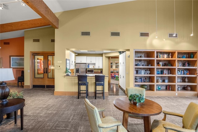 carpeted living area with beam ceiling, visible vents, and high vaulted ceiling